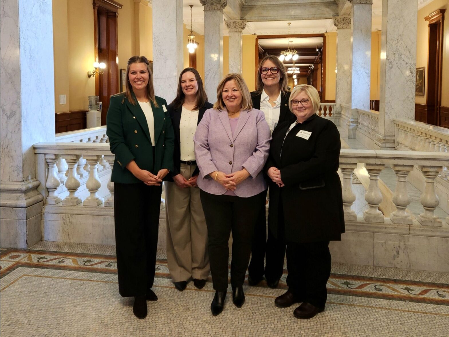 Group of five ladies stand smiling for a photo.
