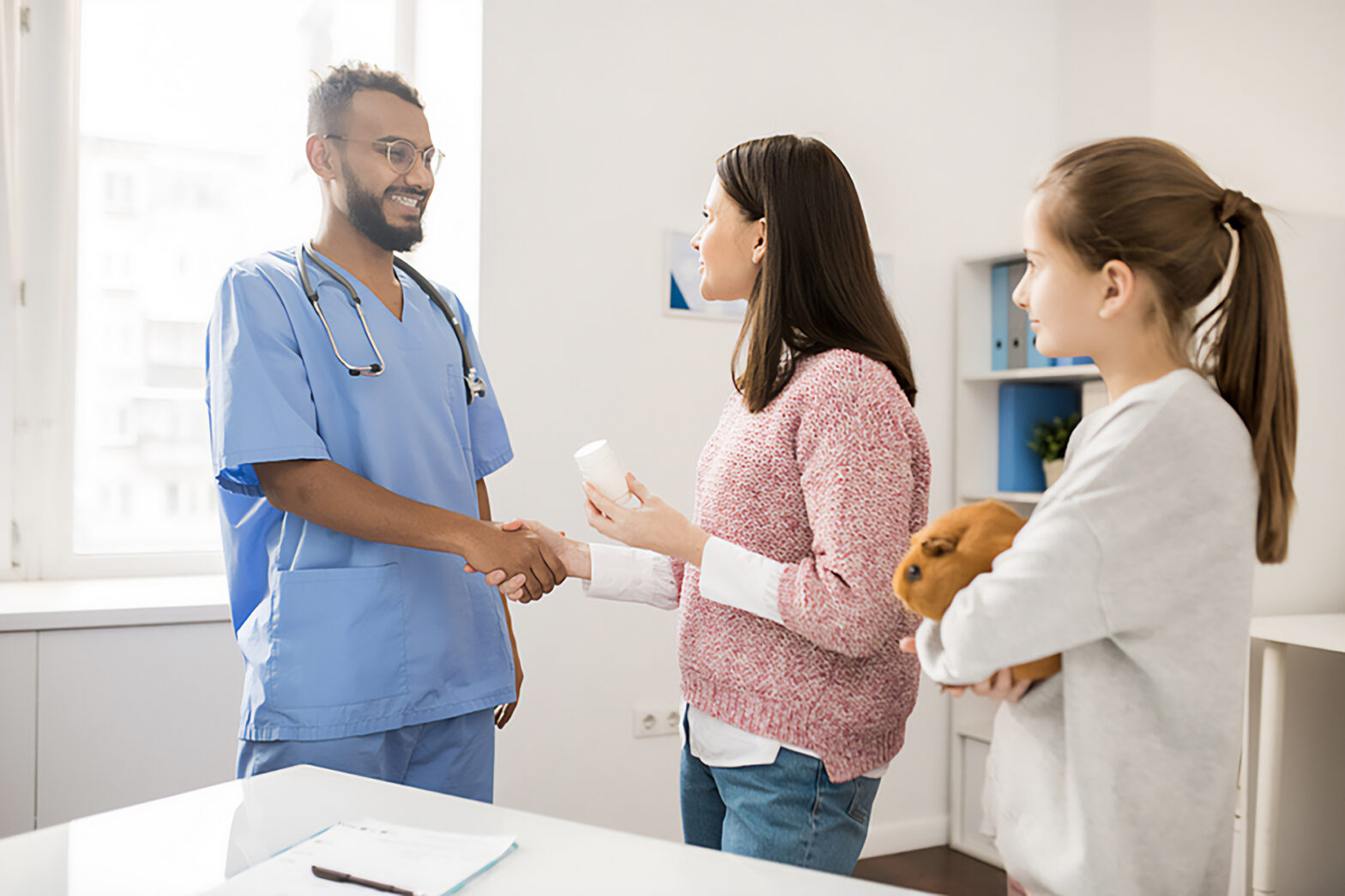Young happy owner of guinea pig shaking hand of veterinarian after consultation and medical examination.