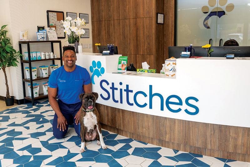 man kneeling and smiling with dog in front of him