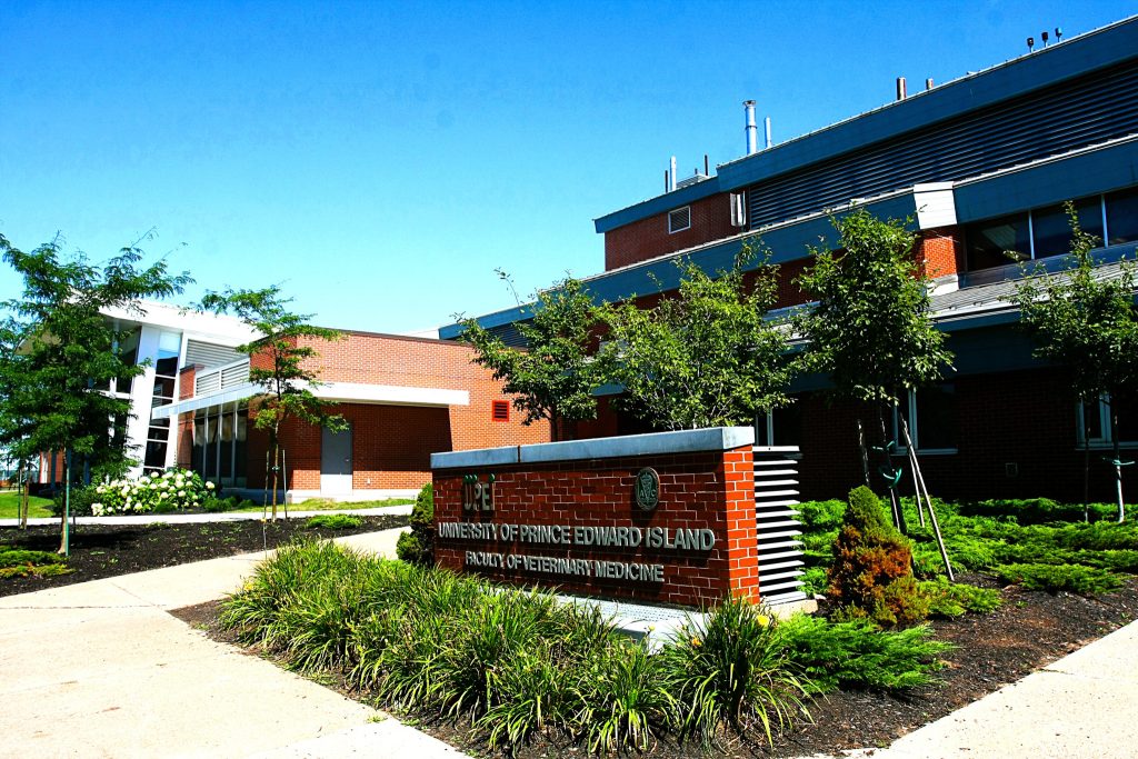 Modern building of the University of Prince Edward Island, with a stone sign for the Faculty of Veterinary Medicine and landscaped greenery.